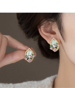 Detailed shot of vintage gold-trimmed oval floral earrings with pearl and green enamel
