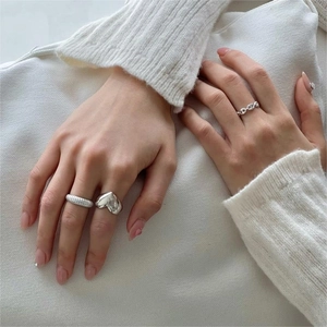 Close-up of a 925 sterling silver ring set featuring heart, thread, and chain designs