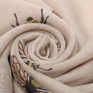 Close-up of bee print scarf fabric with golden glitter accents and textured spiral folds