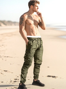 Army green cargo pants for men featuring large flap pockets and elastic cuffs in outdoor beach