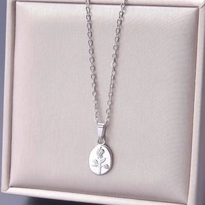 Macro shot of silver oval pendant with embossed rose on a fine chain jewelry box