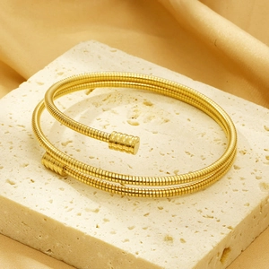 Detail of 18k gold plated multi-layer cable spring bracelet on a stone pedestal
