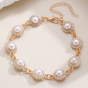Dettaglio del bracciale dorato con maglie a fiore di perla e chiusura a moschettone