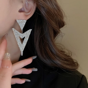 Close-up of oversized silver triangular earrings with shimmering pavé zircon stones
