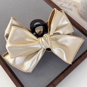 Close-up of large golden PU leather bow hair claw clip with detailed edge stitching