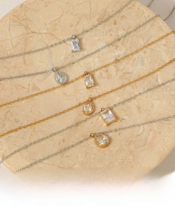 Detail of gold and silver layered necklaces with zircon pendants on marble base