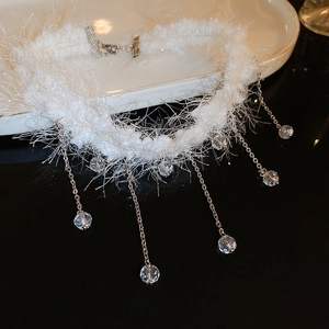 Detail of white faux fur choker featuring silver metal chains and crystal pendant