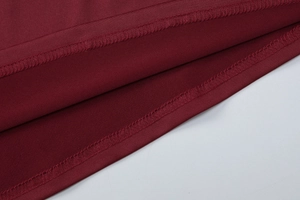 Dettaglio delle cuciture taglia-cuci su abito in maglia bordeaux di alta qualità