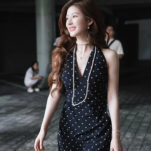 Detail of elegant long pearl necklace worn with a black polka dot dress on model