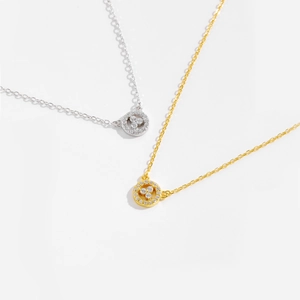 Close-up of s925 silver and gold necklaces with circular diamond-encrusted pendants