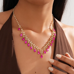 Close-up of gold tiered necklace featuring pink teardrop crystals and diamond accents
