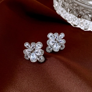 Macro shot of silver flower earrings with zircon inlays on a dark textured surface
