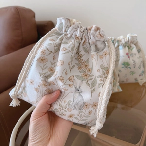Vue détaillée de la pochette en velours crème avec imprimé floral et lapin délicat
