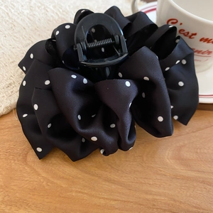 Detail of a black polka dot silk fabric hair claw clip set on a wooden table setup