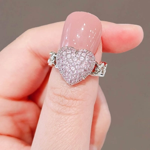 Pink heart-shaped crystal ring with silver chain band design on a model's finger
