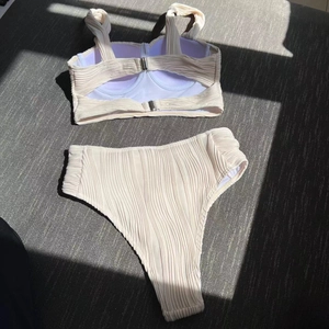 Macro detail of cream crinkle fabric on a high-waisted two-piece bikini set