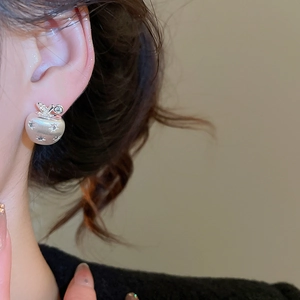 Macro detail of silver apple earring featuring brushed metal texture and sparkling zircon