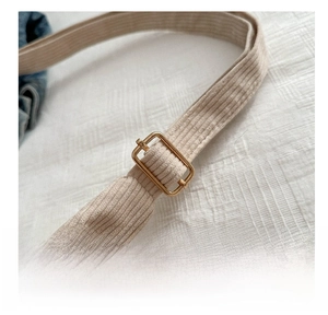 Close-up of adjustable golden metal buckle on beige corduroy tote bag strap