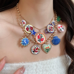 Detail of colorful enamel charms necklace with heart, star, and flower on gold chain