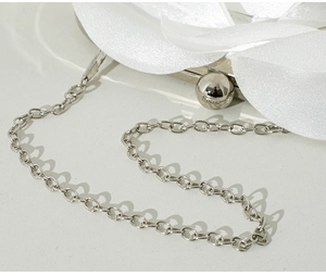 Close-up of white satin flower detail and silver spherical clasp on evening clutch bag