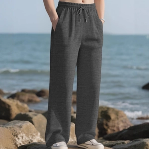 Casual dark grey vertical stripe wide-leg trousers with drawstring waist on beach rocks