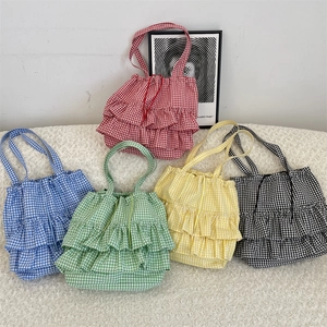 Detail view of colorful plaid canvas tote bags with layered ruffle trim and drawstring closure