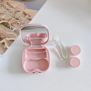 Pink portable contact lens case set with mirror and tools on white background
