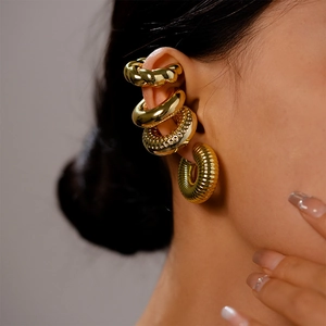 Detail of four-piece gold cuff earring set featuring twisted, smooth, and textured metal designs