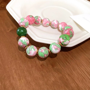 Detailed macro view of pink and green marbled beads with gold spacers on a ceramic plate