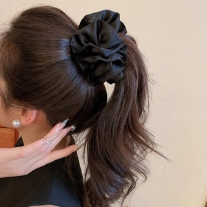Chouchou élégant en satin noir avec strass sur un mannequin avec queue de cheval haute