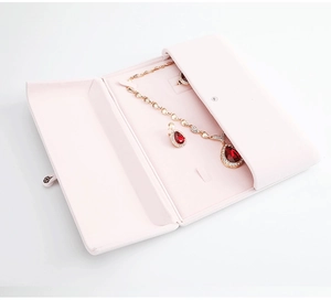 Detailed interior of a pink velvet jewelry roll showcasing rings and necklaces