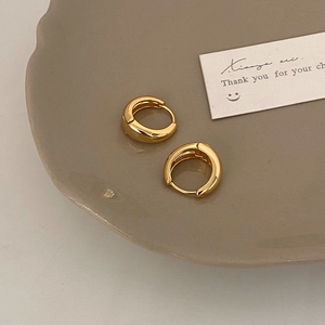 Detailed view of polished golden huggie earrings with a reflective mirror finish