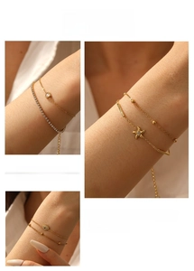 Dettaglio di bracciali dorati a strati con ciondolo a stella, zircone a cuore e occhio