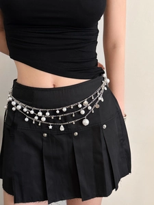 Detail shot of a silver layered waist chain with pearls and star pendants on a model