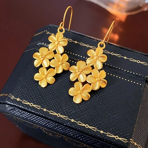 Detailed macro shot of 18K gold flower earrings on a navy blue jewelry box