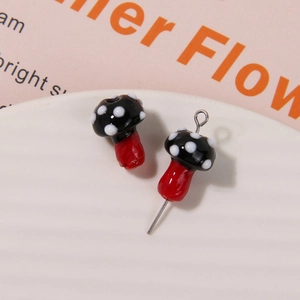 Close-up of black and white polka dot glass mushroom charms for DIY jewelry making