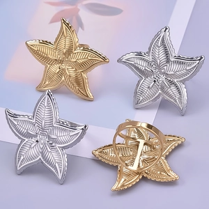 Detail of adjustable starfish rings in gold and silver finishes on a violet background