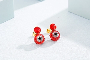 Detail of red globe stud earrings with devil's eye design and white rhinestones