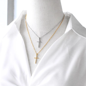 Elegant gold and silver cross pendant necklaces displayed on a model in white