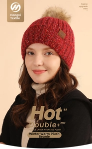 Detail of red winter knit hat with cozy fleece lining and fluffy faux fur pompom