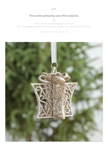 Glittery gold hollow gift box ornament with white ribbon hanging on a Christmas tree