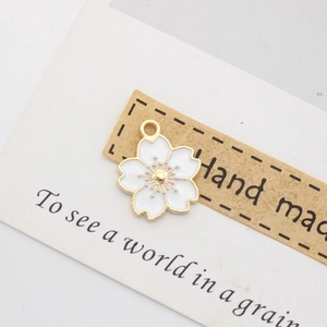 Detailed view of white enamel cherry blossom pendant with gold trim on handmade card