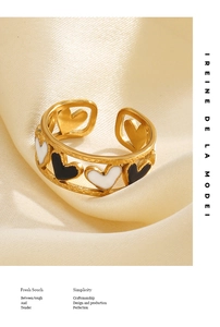 Vue détaillée bague ouverte dorée avec cœurs émaillés noir et blanc en alternance
