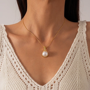Elegant gold necklace with pearl pendant and zircon accents worn on a model's neck