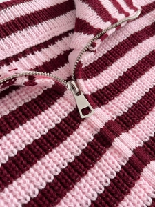 Dettaglio in maglia a righe rosa e bordeaux con elegante cerniera in metallo argentato lucido