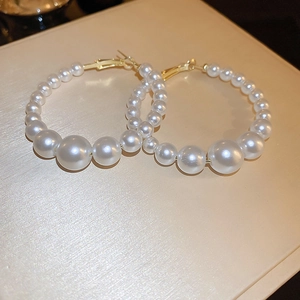 Detailed view of gold hoop earrings featuring a gradient of white faux pearls on silk