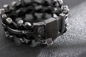 Macro detail of the woven black leather strap and antique silver buckle on the biker bracelet