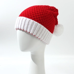 Close-up of red knit Christmas hat with thick weave and soft white fluffy pompom ball