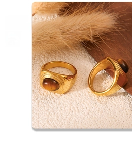Detailed view of gold oval tiger eye ring resting on a textured surface with warm lighting