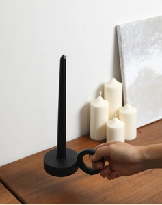 Detail of matte black ceramic candle holder with ring handle in minimalist home setting